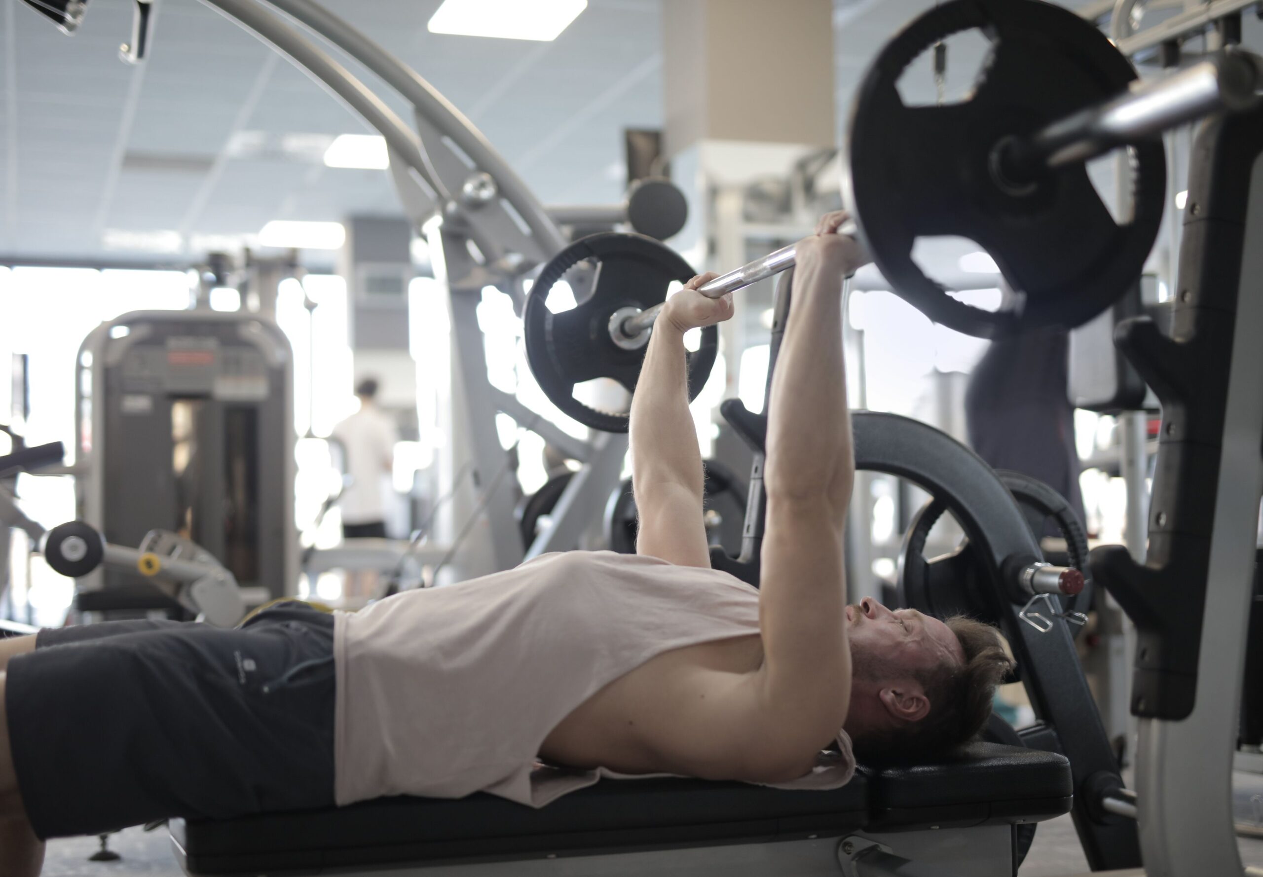 A man in a gym working on bench press for his chest.